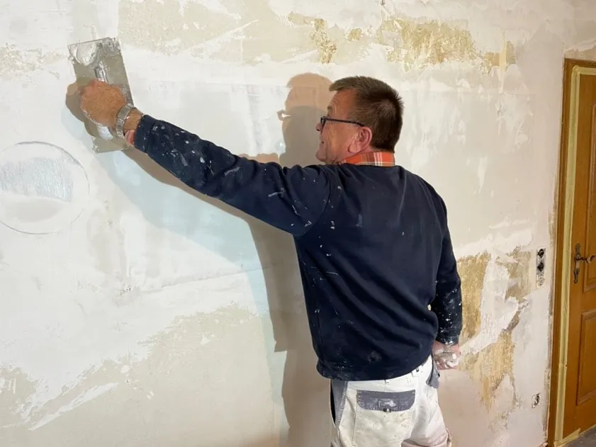 A plasterer skimming over ComfortScrim on the wall of a German house