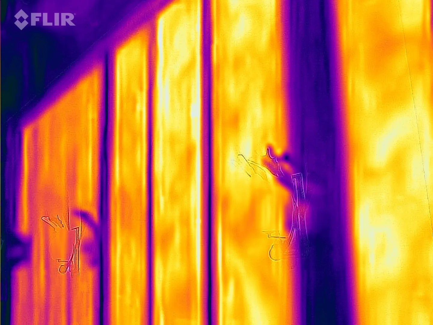 Thermal camera image of heating films glowing evenly behind a wall surface