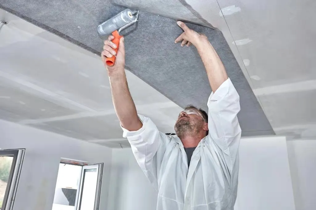 An installer plastering over ComfortScrim on a ceiling
